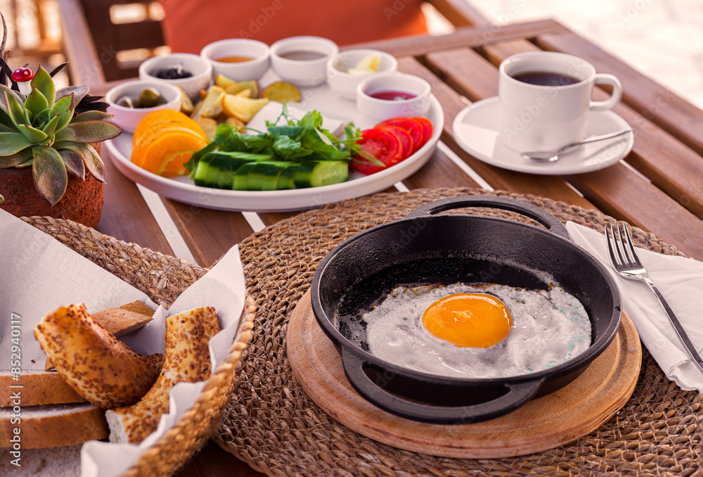 Turkish breakfast at an outdoor cafe with a fried egg and vegetables, and fruit Turkish breakfast at an outdoor cafe with a fried egg and vegetables, and fruit