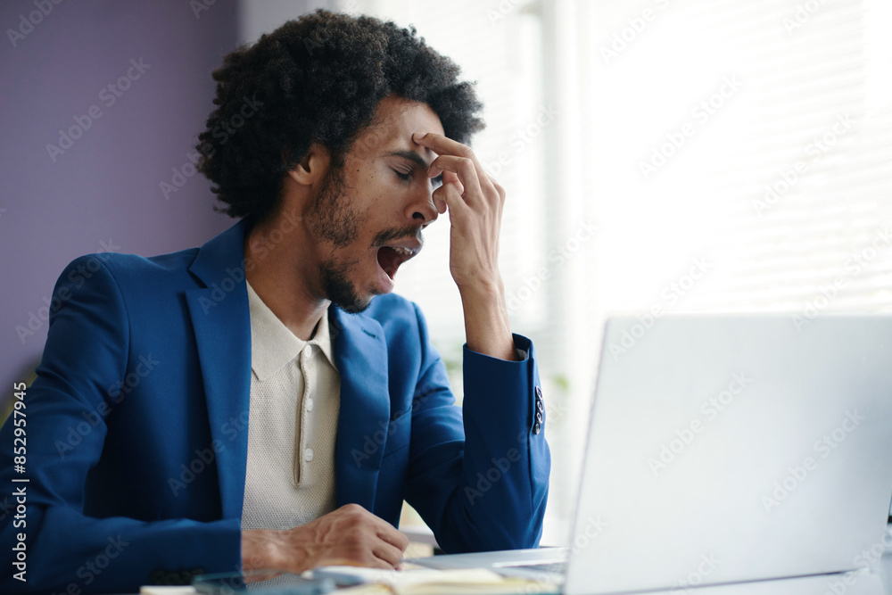 Yawning tired businessman working at office desk Yawning tired businessman working at office desk