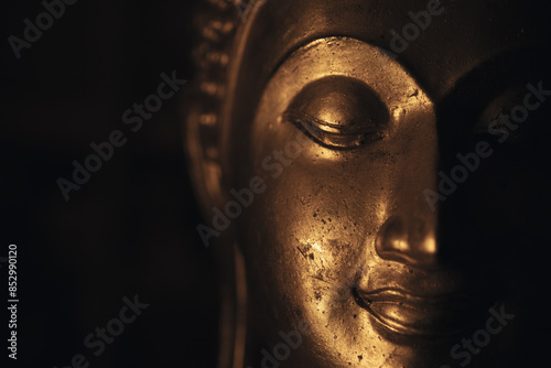A golden Buddha head on a black background with perfectly placed lights and shadows.