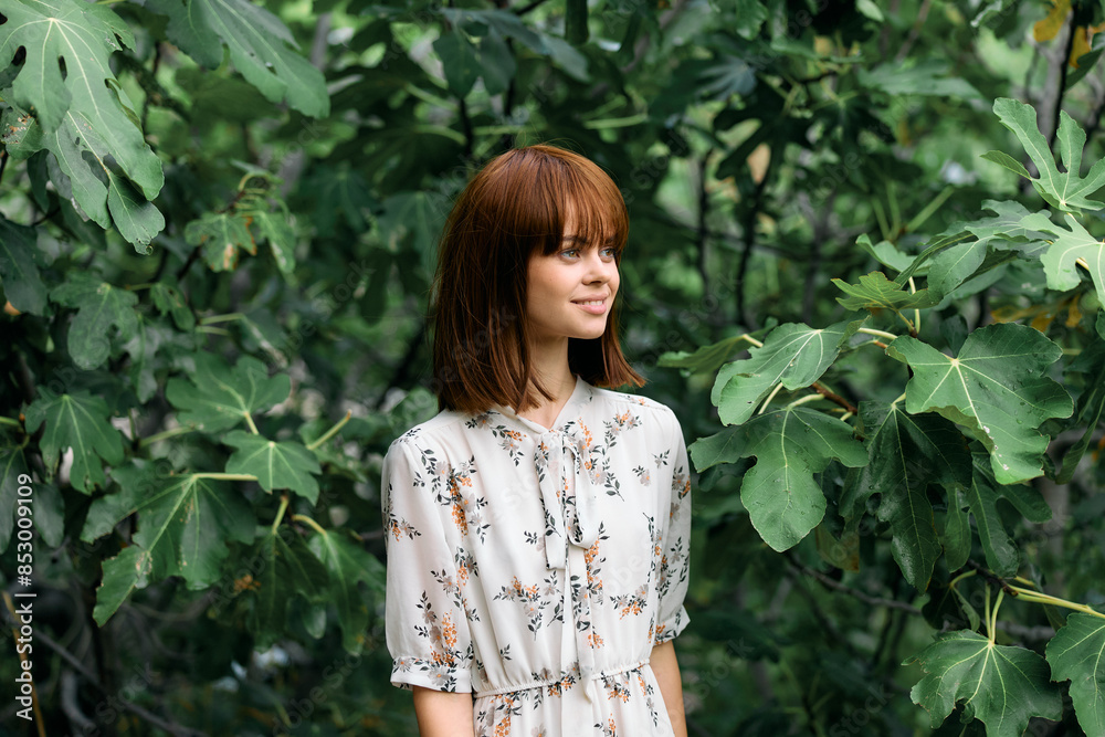 Woman in floral dress surrounded by lush greenery in forest clearing Woman in floral dress surrounded by lush greenery in forest clearing