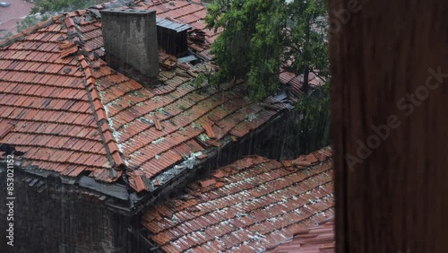 Hail and rain are falling on the briquette roof of the old house. 4k video capture