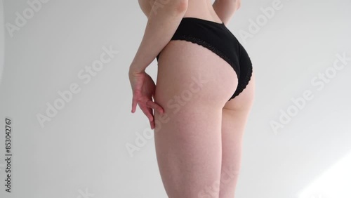 Close-up view of sexy slim caucasian woman standing against grey background. Woman wears black lace panties. Soft focus. Real time video. Fashion and sensuality theme.