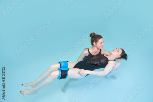 Two woman in pool. Watsu. Blue water rehabilitation massage. Aqua therapy exercise. Physio medical fitness. Sport spa relax. Swim gym class. Adult rehab physiotherapy