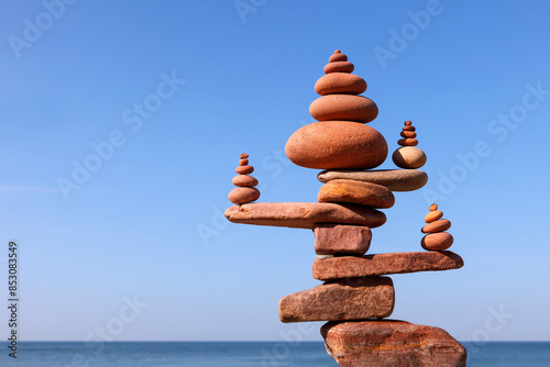 Canvas Print A large rock zen pyramid made of red balanced stones against a background of sea