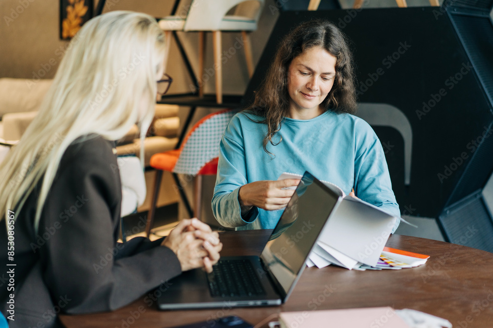 A woman customer consults with a manager on choosing a project design. Two business women are working. A woman customer consults with a manager on choosing a project design. Two business women are working.