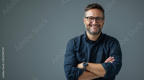 Obraz na płótnie Portrait of a smiling man with glasses and beard, against a plain background. Casual clothing style with folded arms. Suitable for presentations, marketing and professional use. AI w salonie
