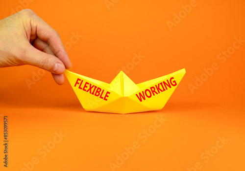 Flexible working symbol. Concept words Flexible working on beautiful yellow paper boat. Beautiful orange paper background. Businessman hand. Business flexible working concept. Copy space.