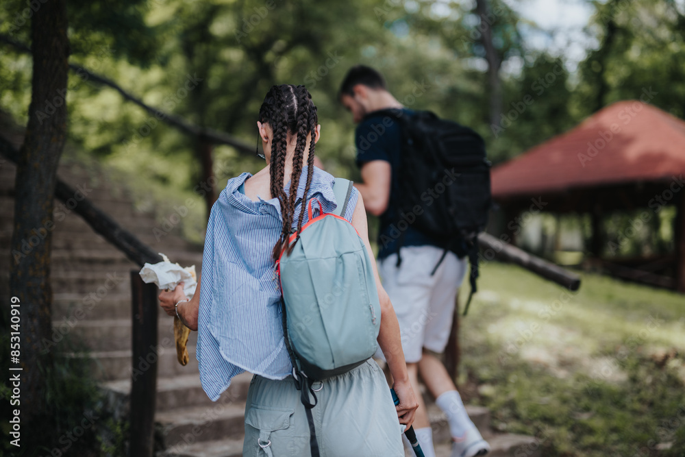 Two hikers with backpacks walking up stairs in a lush forest park on a sunny day. Outdoor adventure and nature exploration. Two hikers with backpacks walking up stairs in a lush forest park on a sunny day. Outdoor adventure and nature exploration.