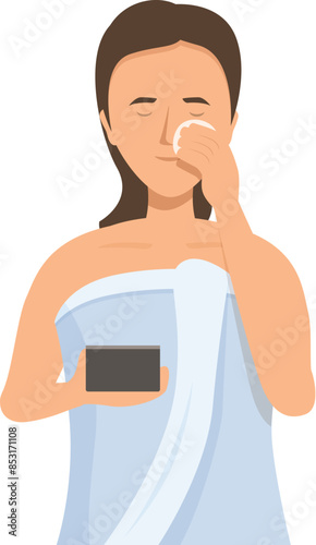 Young woman wearing a towel is removing makeup from her face with a cotton pad and holding a makeup palette