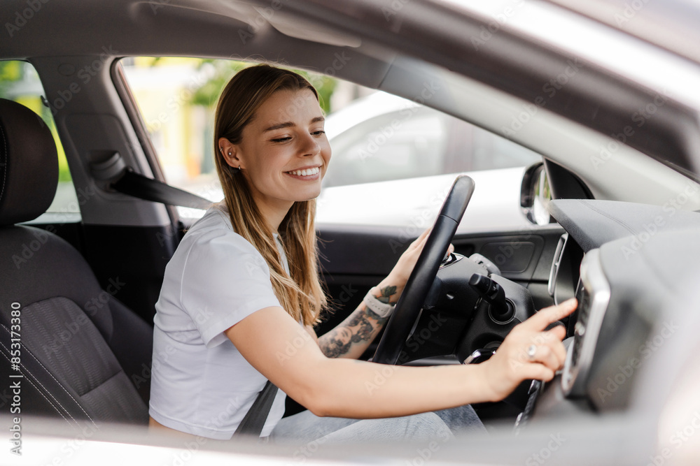 Young woman adjusting car radio while driving modern vehicle Young woman adjusting car radio while driving modern vehicle