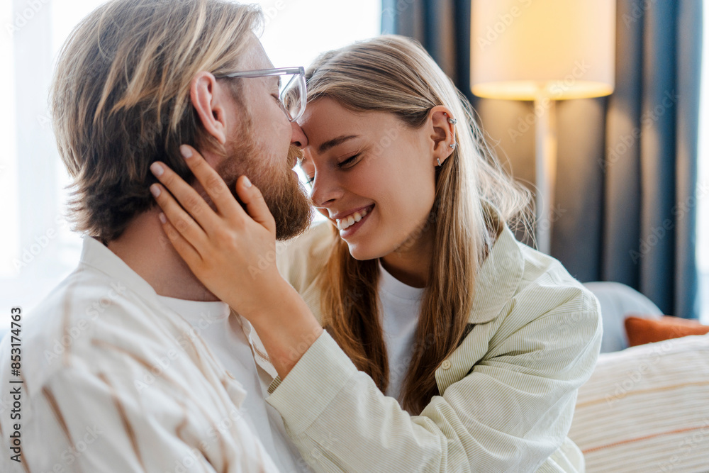 Young couple sharing a tender moment embracing in living room at home Young couple sharing a tender moment embracing in living room at home