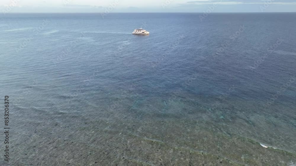 A diving liveaboard ship anchors off the coast of a remote island, Pulau Selu, in the Tanimbar Islands of Indonesia. This tropical area harbors beautiful coral reefs and a wide diversity of fishes. A diving liveaboard ship anchors off the coast of a remote island, Pulau Selu, in the Tanimbar Islands of Indonesia. This tropical area harbors beautiful coral reefs and a wide diversity of fishes.