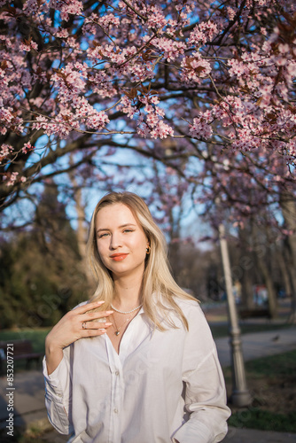 Woman with cherry flowers surrounded by blossoming trees copy space. Beauty and seasonal change and spring bloom season concept.