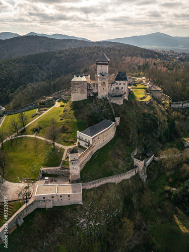 Aerial drone view of famous scenic Trenciansky hrad on high cliff in Slovakia. Overhead panoramic photo of medieval Trencin castle, road and green summer trees of forest, palace of lord on mountain