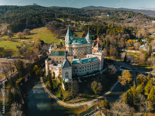 Aerial panoramic view of Bojnicky Zamok, medieval castle in Bojnice, Slovakia. Overhead scene of famous stone fortress and forest to horizon, landscape with historic buildings on hill with moat photo