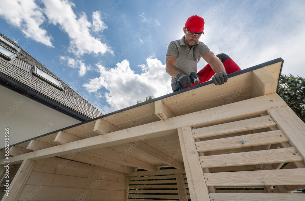 Man Installing Roof On Wooden Structure Man Installing Roof On Wooden Structure