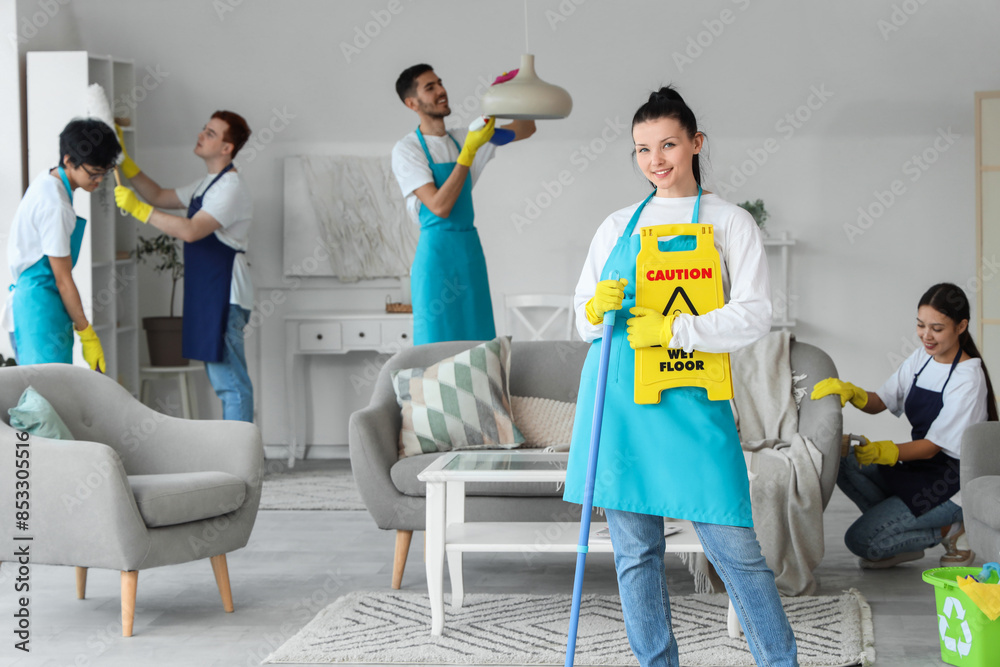 © Pixel-Shot - Female janitor with mop and caution sign in room