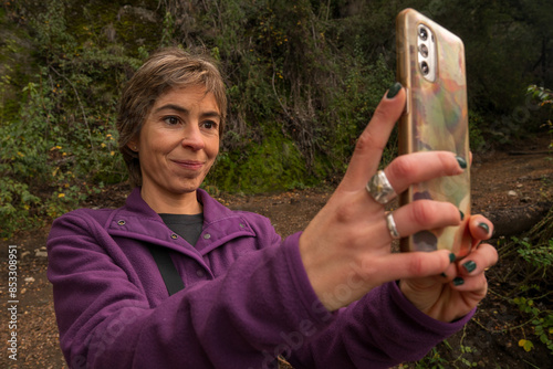 Travel latin woman use cellphone to take photo at forest