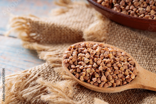 Uncooked Buckwheat in Wooden Spoon on Vintage Burlap, Close-Up