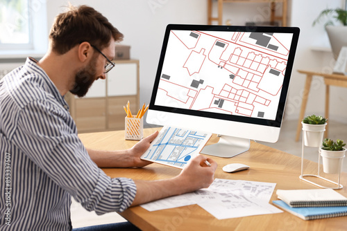 Photography Man working with cadastral map on tablet and computer at table in office