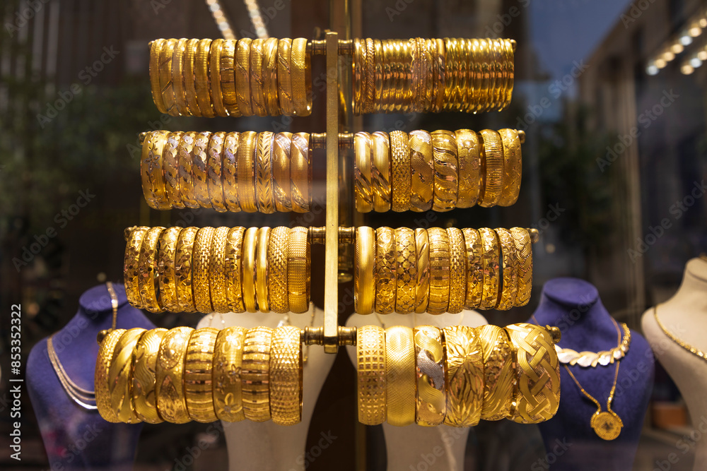 Gold bracelets on display in a store window. Gold bracelets on display in a store window.