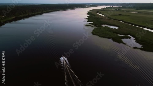 Aerial view of river with speedboat creating wake at sunset, capturing beauty of tranquil landscape photo