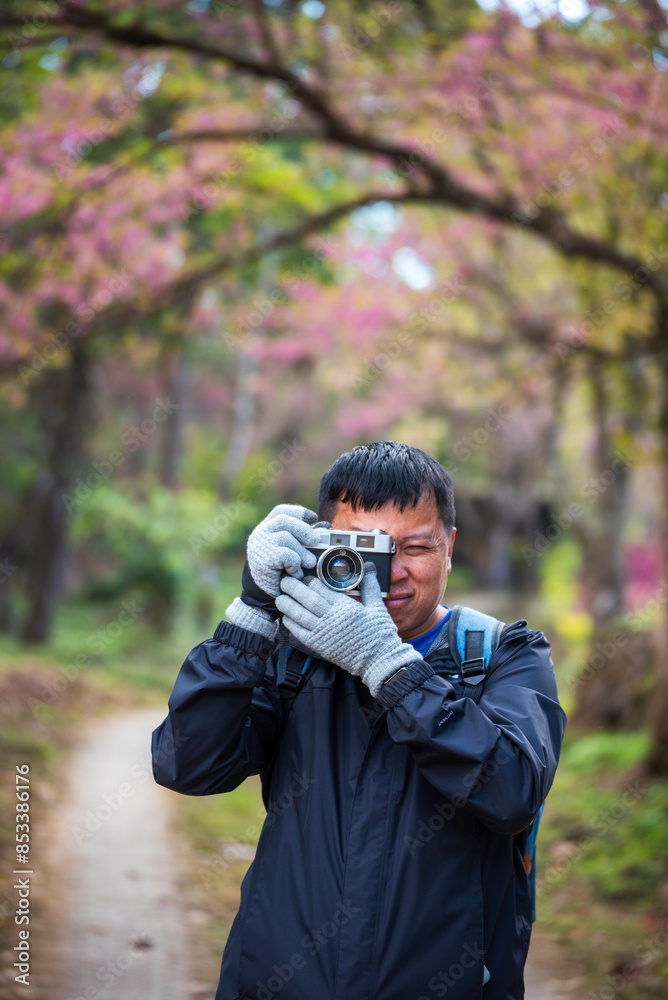 Vertical image Asian man use professional digital camera take a photo. Smiling male photographer look at photo film camera outdoors. Man shooting photo in green nature park. Men hobby lifestyle Vertical image Asian man use professional digital camera take a photo. Smiling male photographer look at photo film camera outdoors. Man shooting photo in green nature park. Men hobby lifestyle
