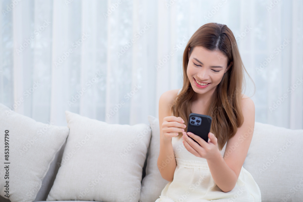 Young asian woman sitting on sofa using smart phone for video call in living room at home, female using social media on phone for chat online and conversation distant with relax, lifestyle concept. Young asian woman sitting on sofa using smart phone for video call in living room at home, female using social media on phone for chat online and conversation distant with relax, lifestyle concept.