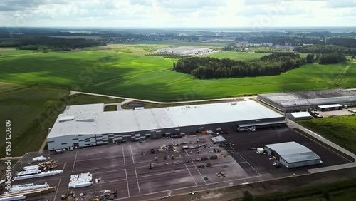 Realtime footage of a large industrial warehouse in a rural setting, from an aerial view, with expansive green fields