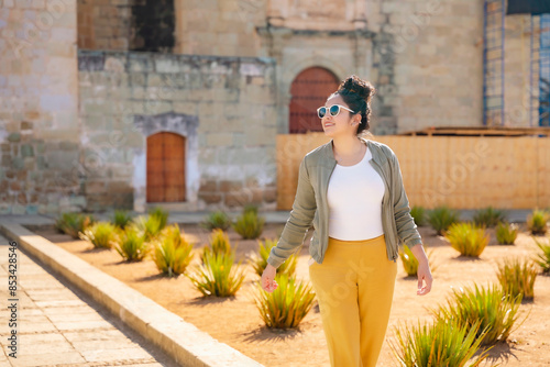 Young Latina woman walking and looking around near Santo Domingo Church. Curious and content. Taken in Oaxaca, Mexico.