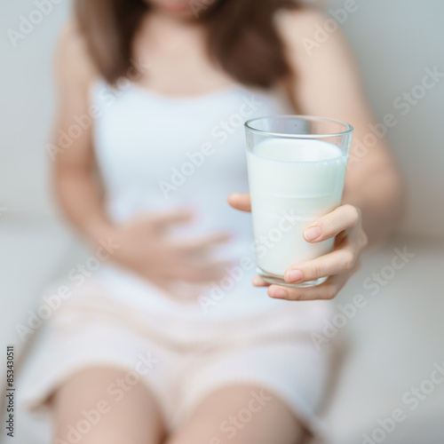 Lactose intolerance and Milk allergy concept. woman hold Milk glass and having abdominal cramps and pain when drink Cow Milk. Symptom stomach ache, Dairy intolerant, Nausea, Bloating, Gas and Diarrhea