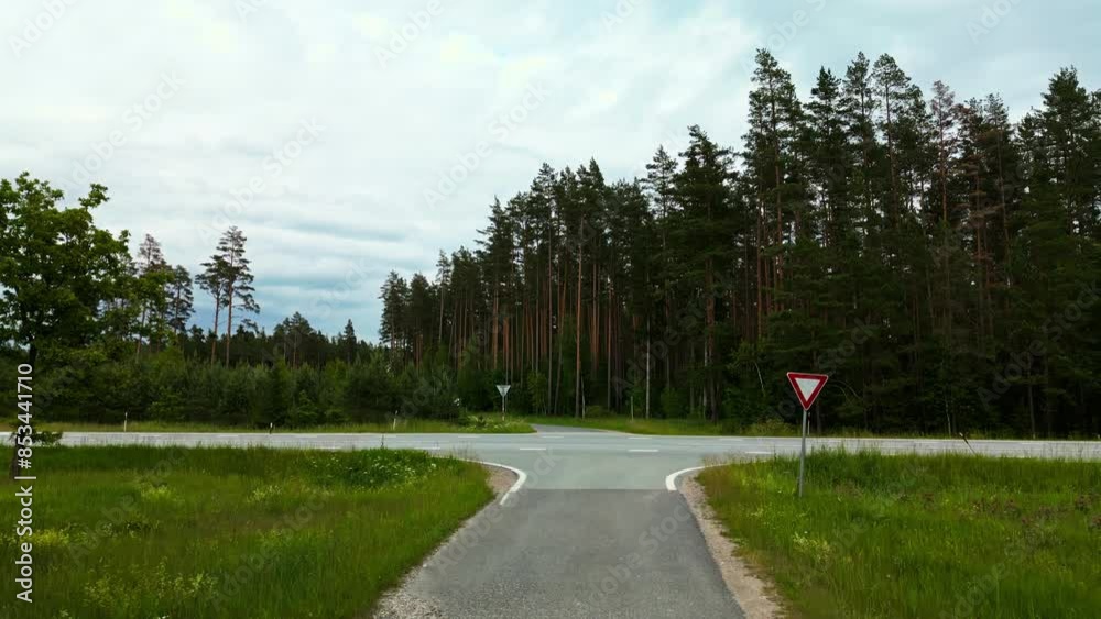 A drone captures a beautiful forest road intersection with a yield sign among greenery and peaceful surroundings A drone captures a beautiful forest road intersection with a yield sign among greenery and peaceful surroundings