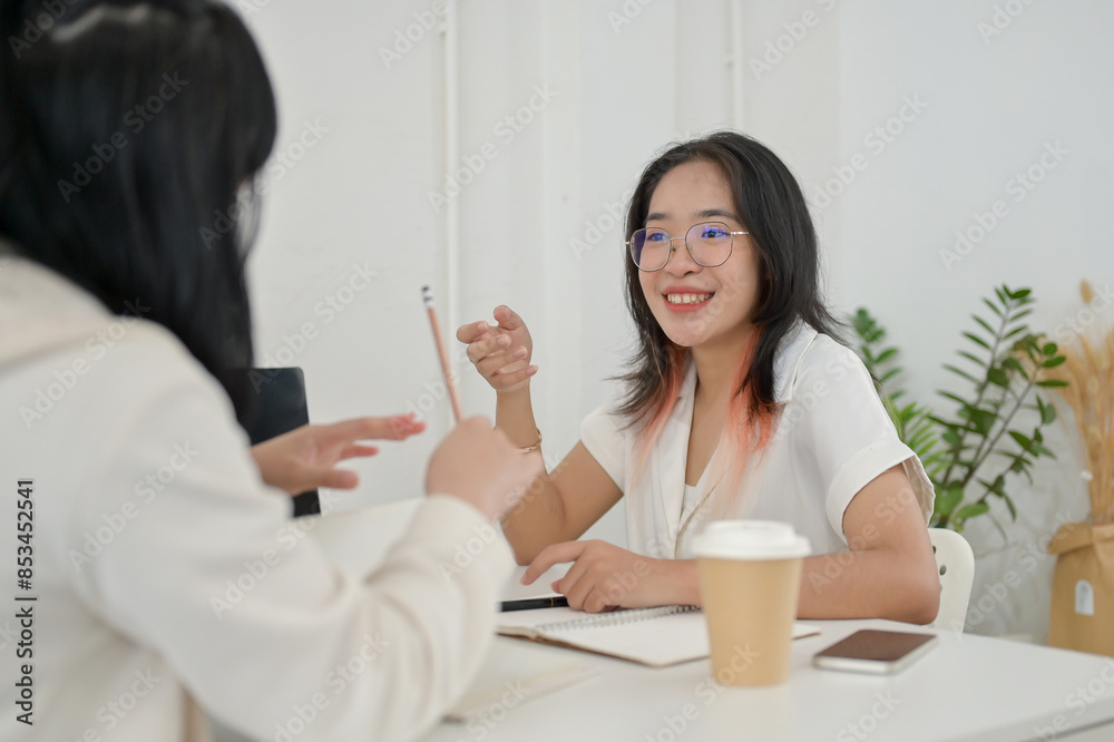 A female college student is meeting her friend at a cafe to work on a project together. A female college student is meeting her friend at a cafe to work on a project together.