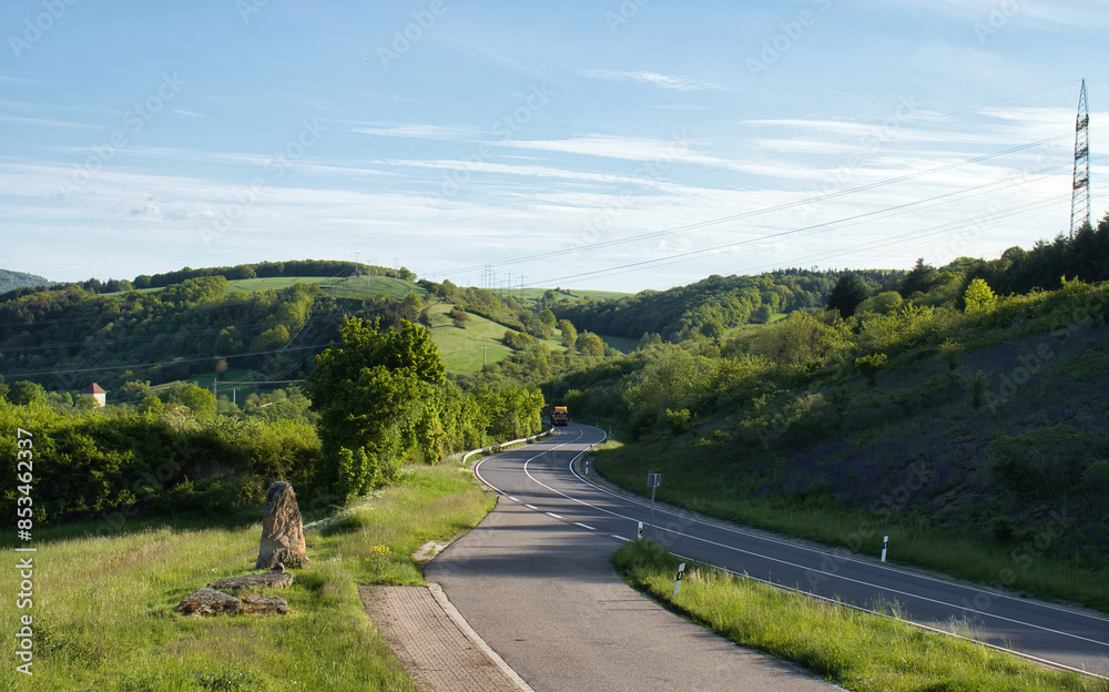 Road through hills with green trees and grass on a sunny spring evening in Rhineland Palatinate, Germany. Road through hills with green trees and grass on a sunny spring evening in Rhineland Palatinate, Germany.