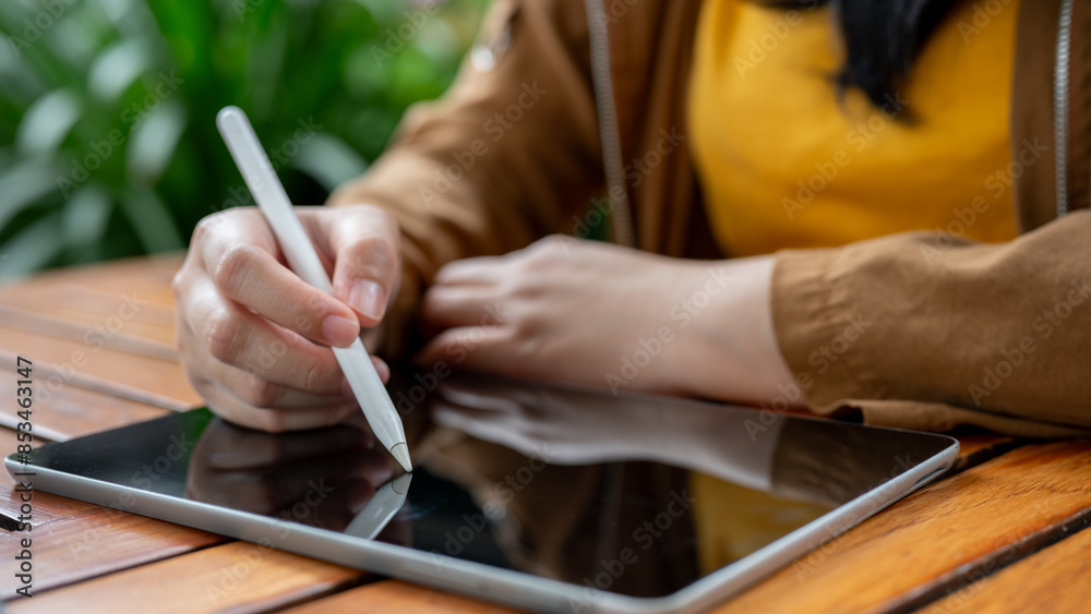 A close-up image of a woman holding a stylus pen, drawing or writing on her digital tablet. A close-up image of a woman holding a stylus pen, drawing or writing on her digital tablet.