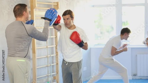 Adult man training boxing punches with sparring partner in studio photo