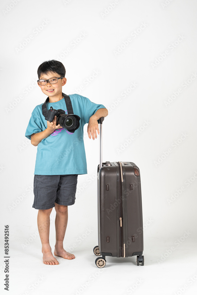 小学生の男の子が夏服でスーツケースとカメラを持っている「夏の旅イメージ」