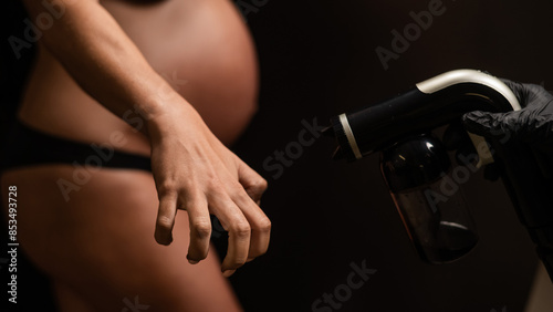 The master applies bronzer with a spray on the hands of a pregnant woman. Instant tan. 
