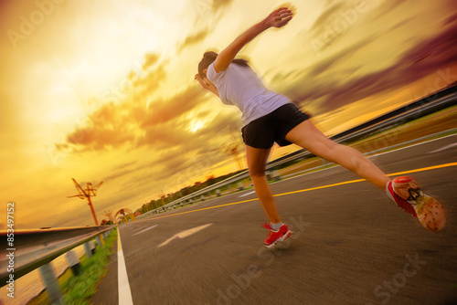 Silhouette of young woman running sprinting on road. Fit runner fitness runner during outdoor workout with sunset background with high speed zoom blur effect.	
