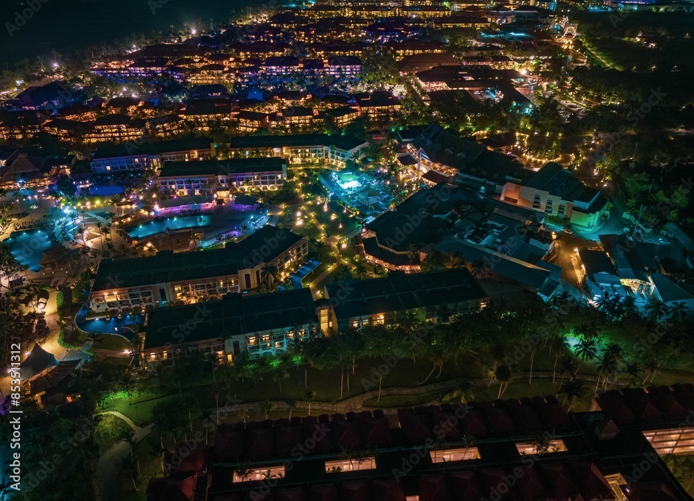 Aerial view of a vibrant resort at night with illuminated buildings and pools Aerial view of a vibrant resort at night with illuminated buildings and pools