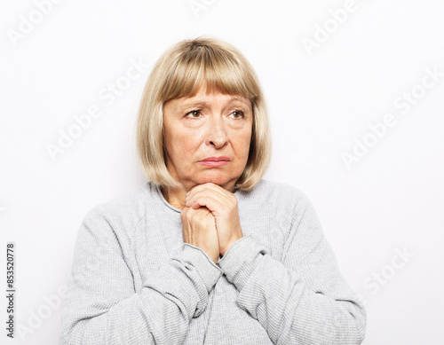 Lifestyle, health and old people concept: An elderly woman holds her hands near her heart, her heart hurts