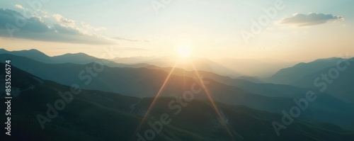 Breathtaking sunset over mountain range with glowing rays and silhouette peaks under a clear sky, creating a serene and peaceful landscape.