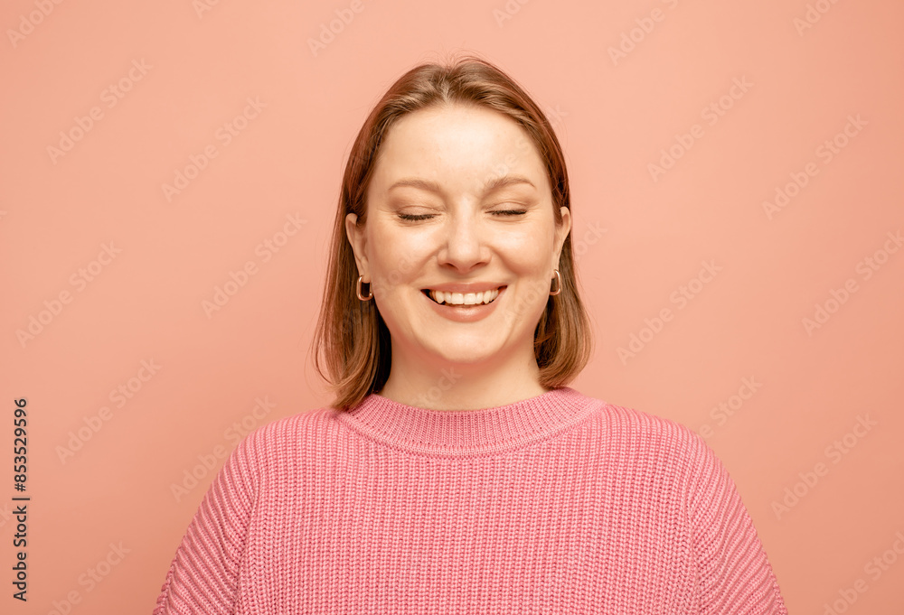 Portrait of cheerful pretty woman with closed eyes wearing pink sweater over pink background