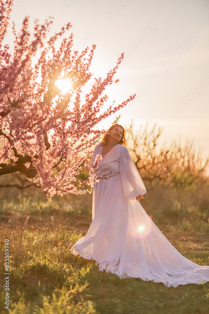 Woman blooming peach orchard. Against the backdrop of a picturesque peach orchard, a woman in a long white dress enjoys a peaceful walk in the park, surrounded by the beauty of nature. Woman blooming peach orchard. Against the backdrop of a picturesque peach orchard, a woman in a long white dress enjoys a peaceful walk in the park, surrounded by the beauty of nature.