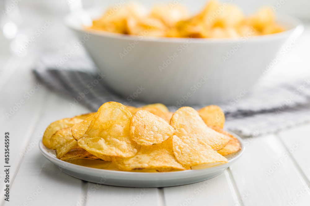Crispy Potato Chips on plate on white table. Crispy Potato Chips on plate on white table.