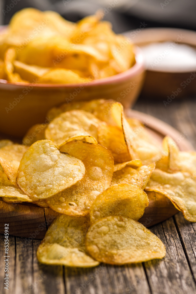 Crispy Potato Chips on cutting board on wooden table. Crispy Potato Chips on cutting board on wooden table.