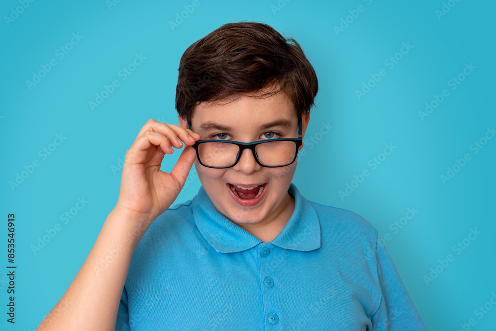 Fototapeta premium A funny handsome boy, dark-haired, wearing glasses and a blue T-shirt,