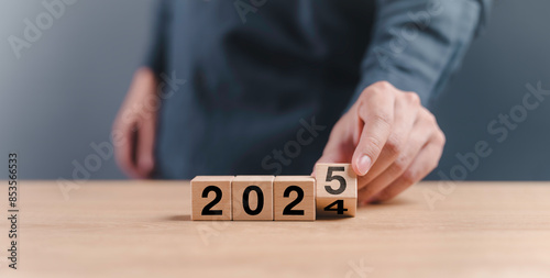 Obraz na płótnie businessman hand assemble wooden block cube to status from 2024 to 2025 new year. goals trends 2025 analytical planning to growth strategy digital marketing, profit income and technical analysis w salonie