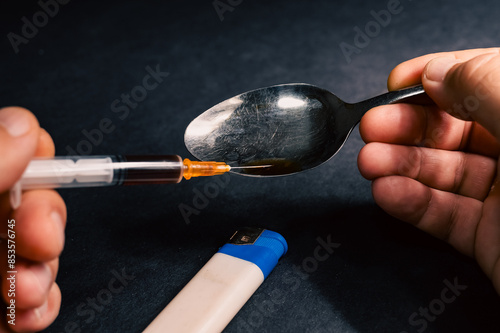 Drug addiction concept. The syringe is filled with heroin prepared in a spoon. Dark background photo