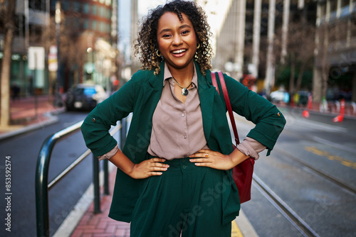 Happy young beautiful businesswoman with arms akimbo standing on street